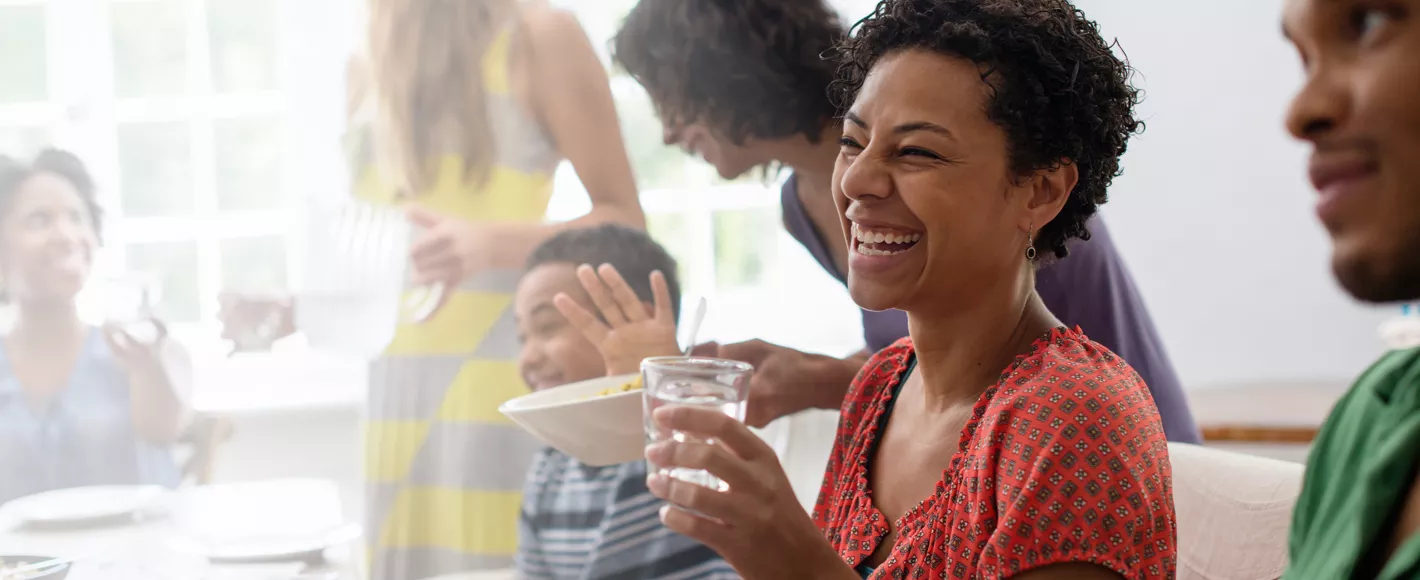 group of people laughing at a dinner party while drinking water